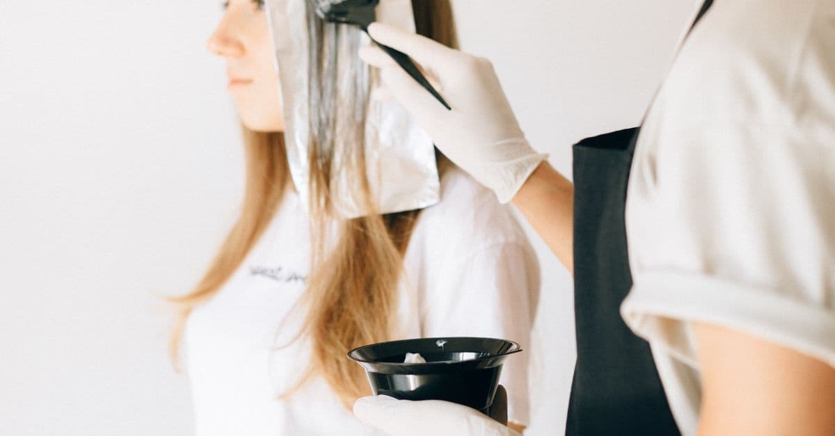 Colourist applying lightener to a client's hair in a salon