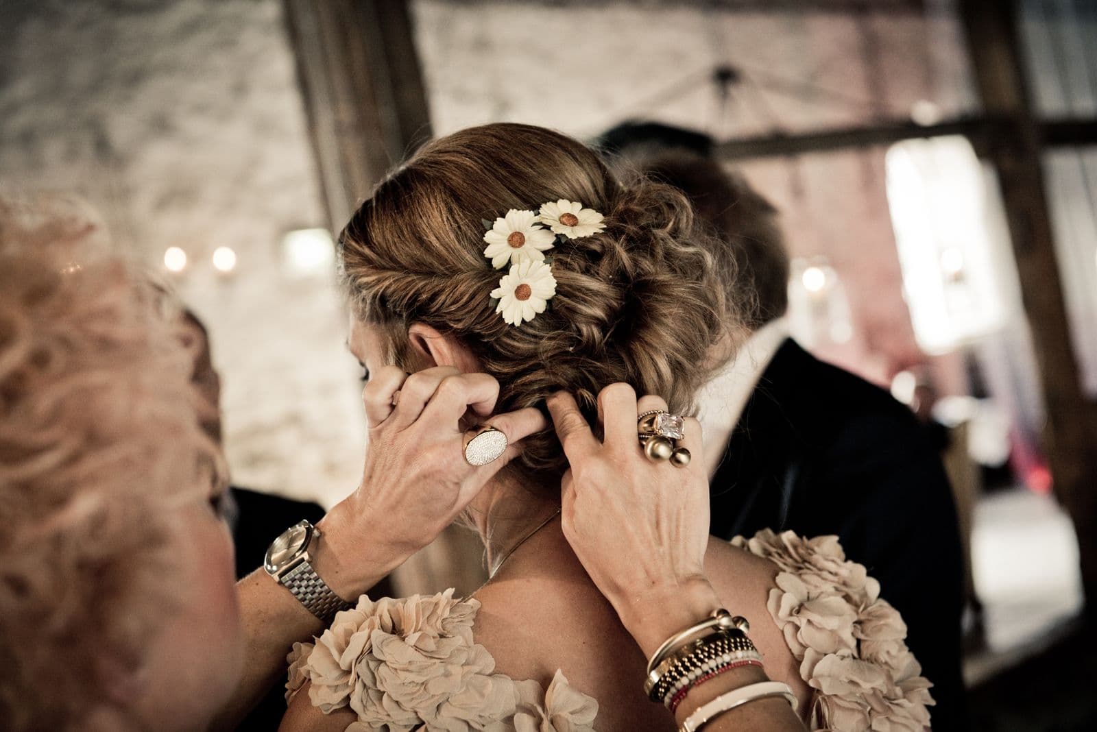 Illustrative stock photo of a hairstylist pinning a wedding updo with white floral accessories; not a Mosaic client or result