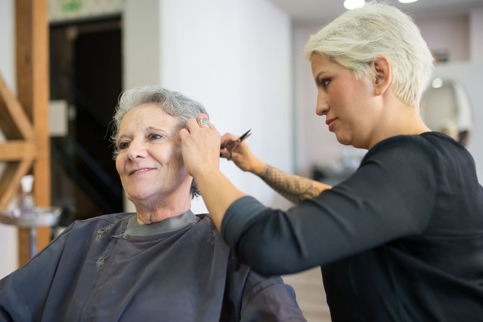 Illustrative Pexels stock photo of a hairstylist trimming an older client with white hair in a salon; not Mosaic staff, a colour-blending procedure, or a client result
