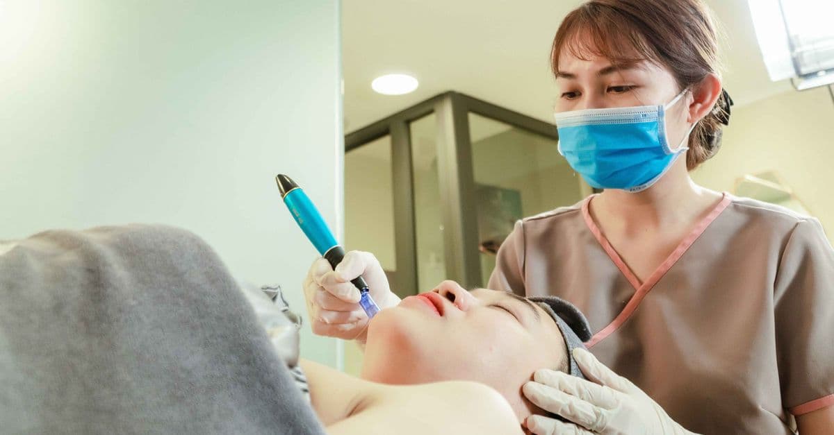 Client receiving a professional microneedling-style facial treatment in a skincare clinic